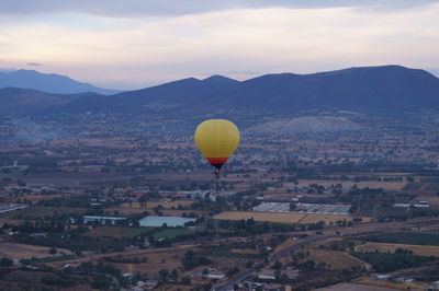 Hot air balloon flying over city against sky