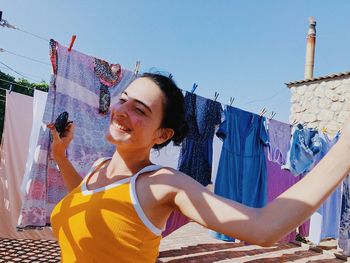 Close-up of smiling young woman against sky