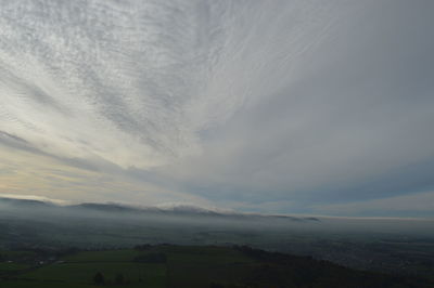 Scenic view of landscape against cloudy sky during sunset