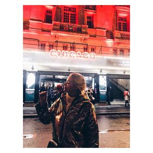 Woman standing by illuminated text on sidewalk in city