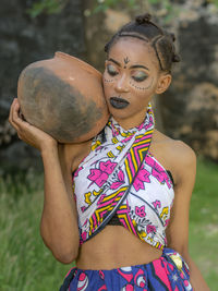 Portrait of woman holding camera while standing on field