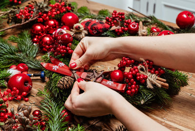 Cropped hands of woman holding christmas decorations on table