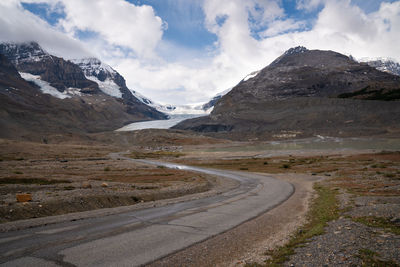 Road leading towards snowcapped mountains against sky