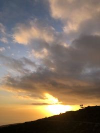 Scenic view of dramatic sky over silhouette landscape during sunset