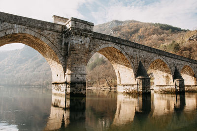 Arch bridge over river against sky