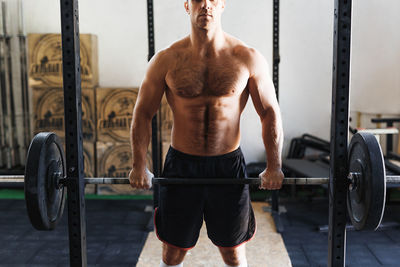 Muscular man lifting dumbbell in gym