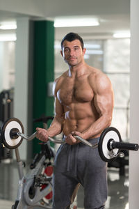 Portrait of shirtless young man exercising in gym
