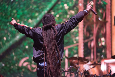 Rear view of man with arms outstretched standing in forest