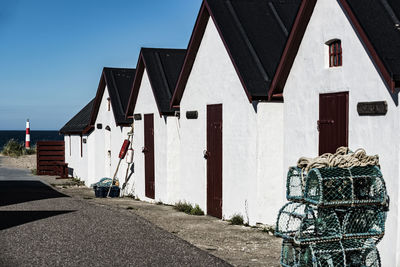 Lobster traps by beach huts on sunny day