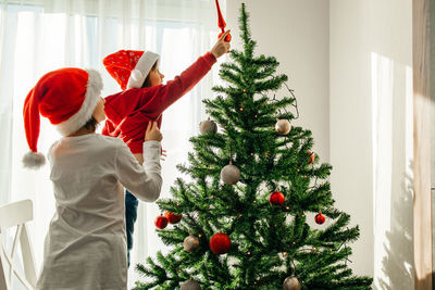 Midsection of woman holding christmas tree at home