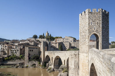 Arch bridge over buildings against clear sky