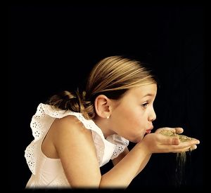 Side view of young woman against black background