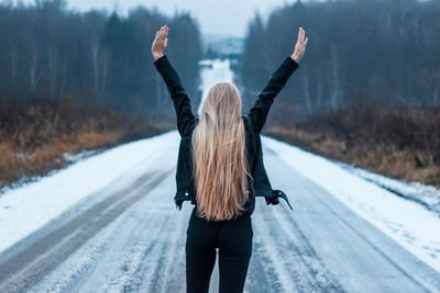 Rear view of woman standing on snow covered road