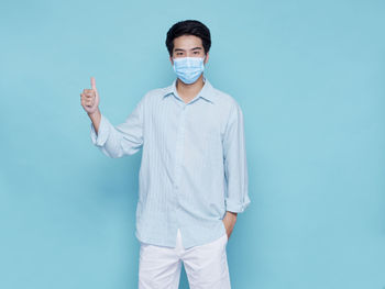 Portrait of young man standing against blue background