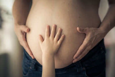 Big sisters hand touches pregnant mams belly