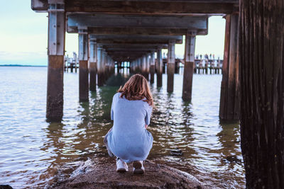 Rear view of woman taking pictures under a pier 