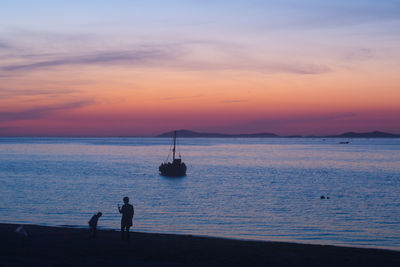 Silhouette people on beach against sky during sunset