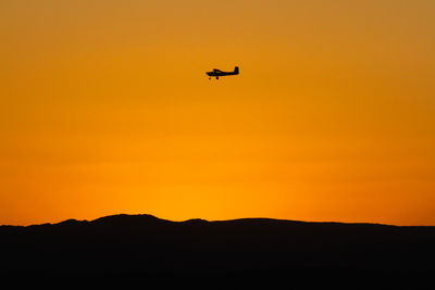 Low angle view of silhouette airplane flying against clear sky