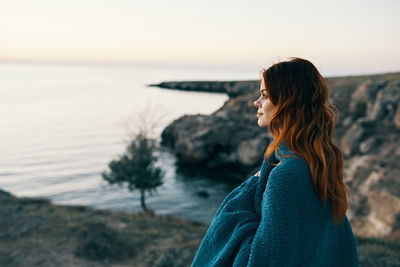 Woman looking at sea against sky during sunset