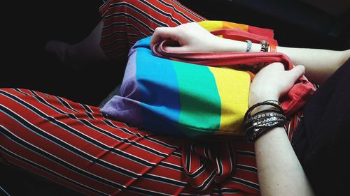 Midsection of woman sitting on multi colored sofa