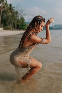 A young woman in a gold dress dancing in the sea