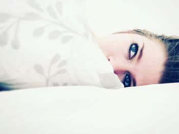 Portrait of beautiful young woman lying on bed