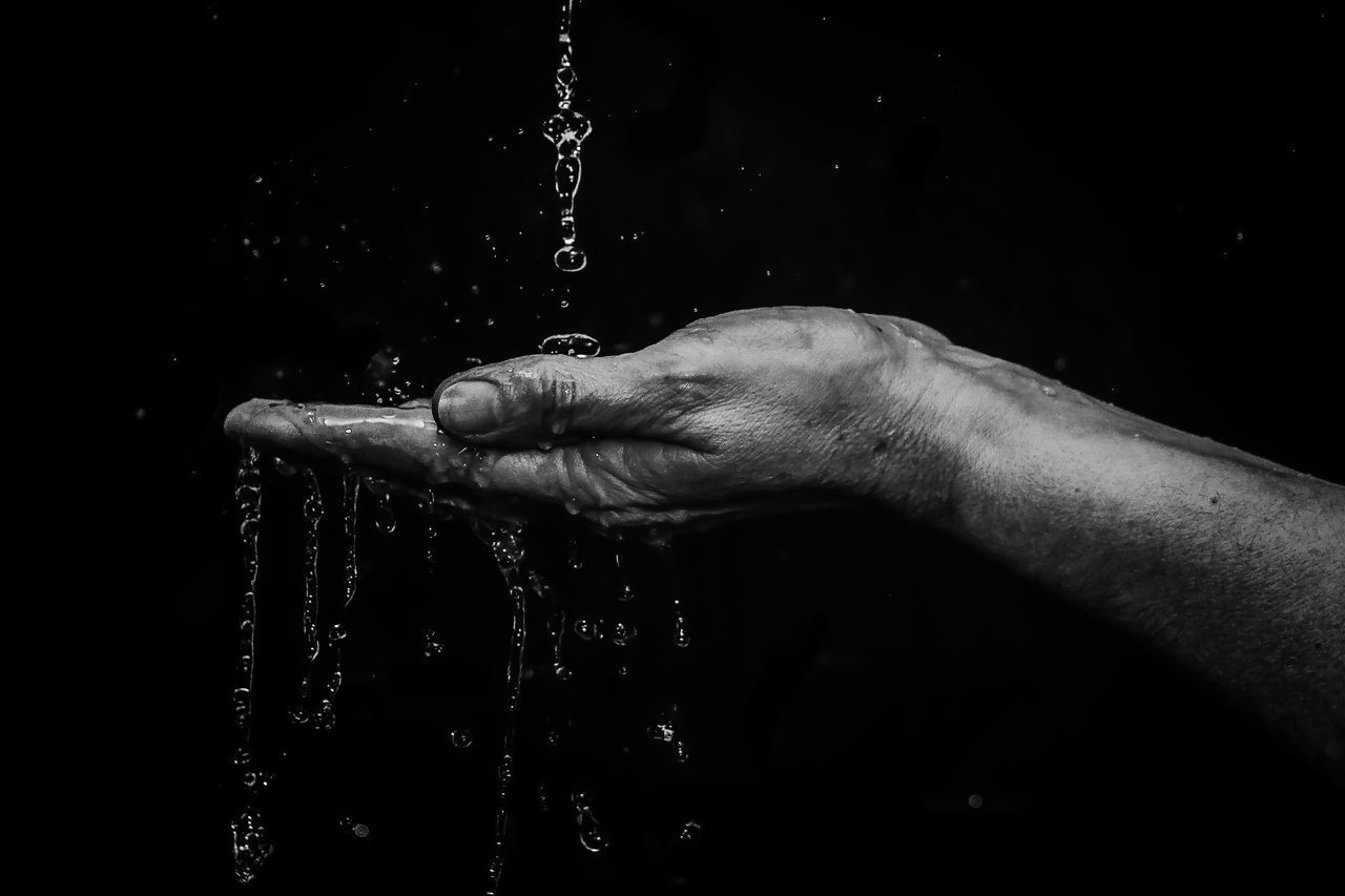 CLOSE-UP OF HAND TOUCHING WATER SPLASHING