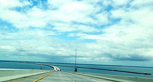 Bridge over sea against cloudy sky