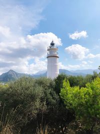 Lighthouse amidst plants and buildings against sky