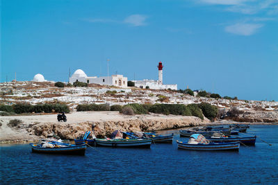 Boats in sea against cloudy sky