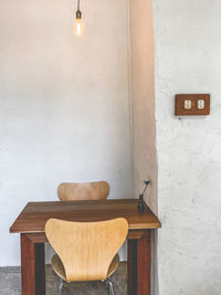 Empty chairs and table against wall in building