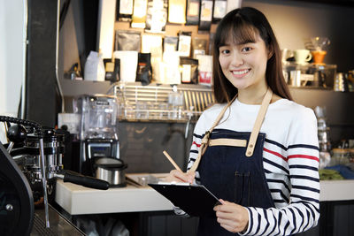 Portrait of a smiling young woman standing in cafe