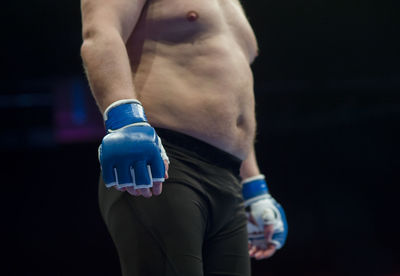 Midsection of shirtless boxer standing in boxing ring