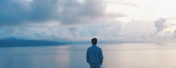 Rear view of man looking at sea against sky