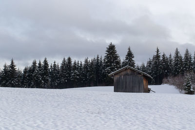 House in snow covered land against sky