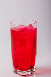 Close-up of red wineglass against white background