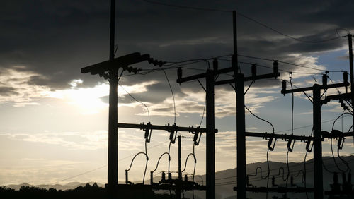 Low angle view of silhouette electricity pylon against sky during sunset