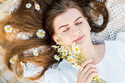High angle view of woman lying on bed while holding flowers