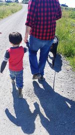 Rear view of father and son on road