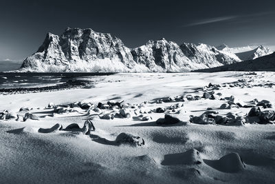 Scenic view of sea by snowcapped mountain against sky