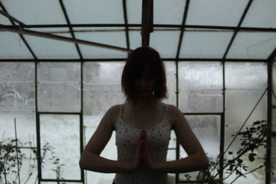 Portrait of woman standing against window