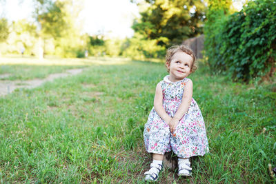 Cute girl standing on grass against plants