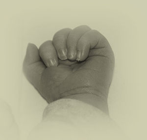 Cropped image of baby hand against white background