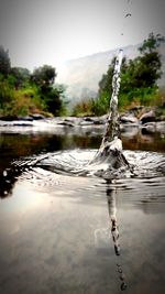 Close-up of water flowing over lake against sky