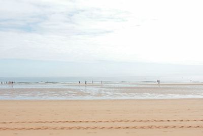 View of calm beach against cloudy sky