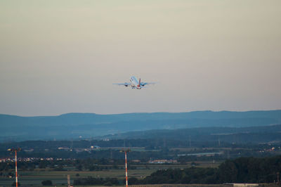 Airplane flying over landscape against clear sky