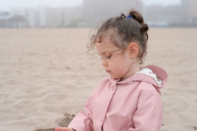 Expressive young girl is playing in sand on a foggy day