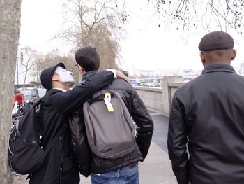 Rear view of men standing against the sky