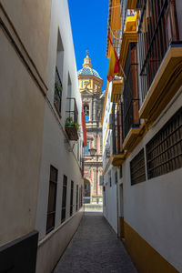 Narrow alley amidst buildings leading towards cathedral in city against sky