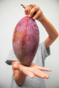 Close-up of hand holding apple against white background